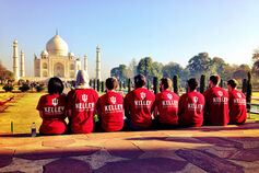 Students wearing red Kelley School of Business shirts sit on a ledge looking at the Taj Mahal.